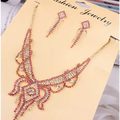 A sparkling pink and gold rhinestone american exaggerated butterfly jewelry set with intricate floral designs and matching earrings