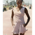 A woman wearing a beige and white vertical striped romper with ruffled straps, contrasting with the teal ruffled deep v one-piece swimsuit with built-in bra suitable for hot spring boxer use