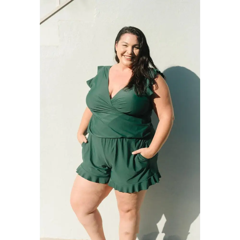 A plus-size woman wears a teal ruffled deep v one-piece swimsuit with built-in bra suitable for hot spring boxer use