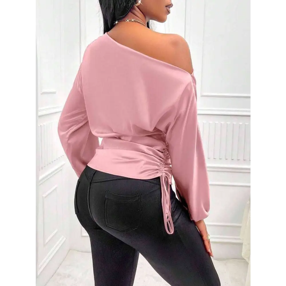 Soft pink satin off the shoulder top with long sleeves and tied ruched waist complementing a teal satin shirt asymmetric style