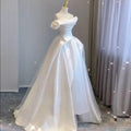 A white temperament princess style french satin gown with a fitted off-the-shoulder bodice and layered tulle skirt