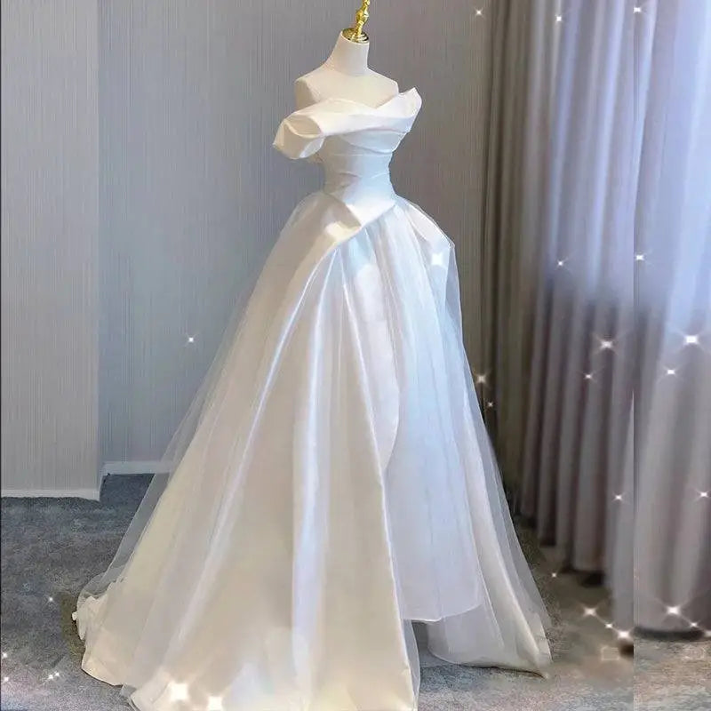 A white temperament princess style french satin gown with a fitted off-the-shoulder bodice and layered tulle skirt