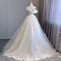 A white temperament princess style french satin gown with a fitted bodice and off-the-shoulder voluminous tulle skirt