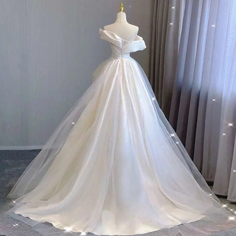 A white temperament princess style french satin gown with a fitted bodice and off-the-shoulder voluminous tulle skirt