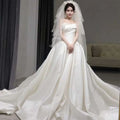 A flowing white temperament princess style french satin wedding gown with a strapless bodice and elaborate veil