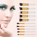 Set of eight makeup brushes with gold ferrules and translucent white handles in a beauty complete kit with maroon case