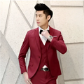 A sharp three-piece burgundy men’s suit with a sleek tailored fit and subtle texture contrasting textured black tailored suits