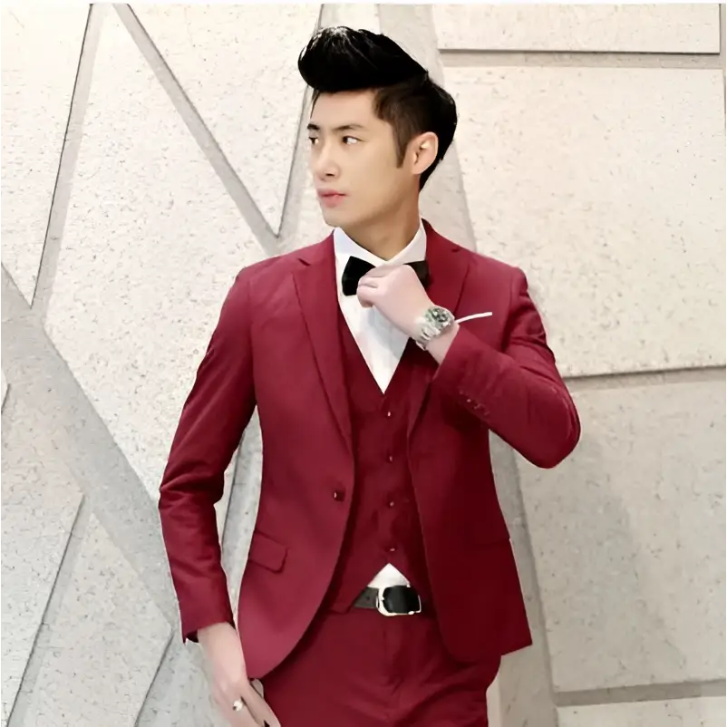 A sharp three-piece burgundy men’s suit with a sleek tailored fit and subtle texture contrasting textured black tailored suits