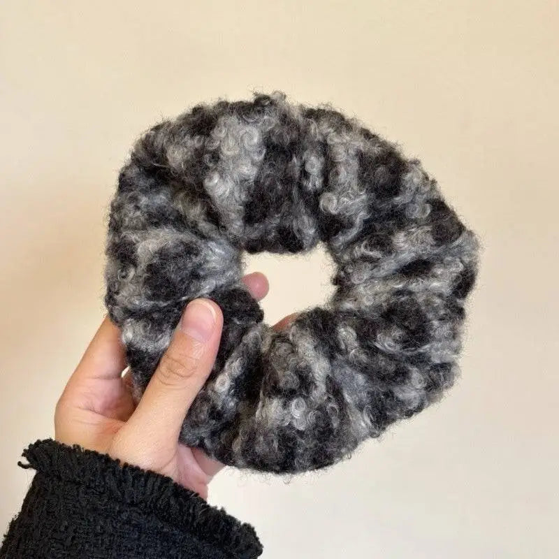 Textured winter plush bow hair clip in gray and black knitted fabric featuring a plush leopard bow design