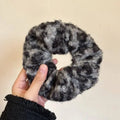 A cozy textured winter plush bow hair clip with a plush leopard bow in black and gray woolly yarn