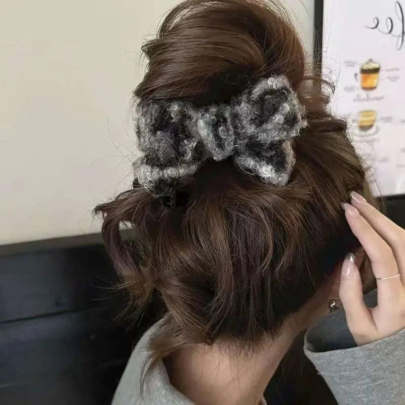 Textured winter plush bow hair clip in gray and black knitted fabric featuring a plush leopard bow design