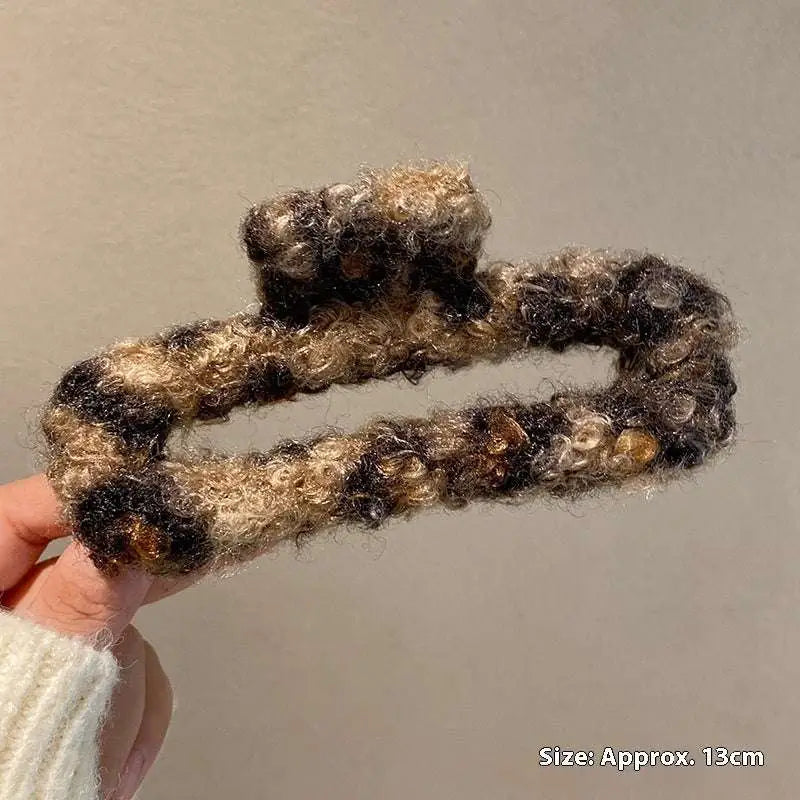 A cozy textured winter plush leopard bow hair clip in curly black and beige faux fur for stylish hair styling
