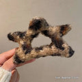 Fuzzy star-shaped bow hair clip in black and beige plaid made from soft textured yarn for textured winter plush use