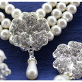 A sparkling silver four-leaf clover brooch with clear crystals and dangling pearl in a three-piece four-leaf clover set