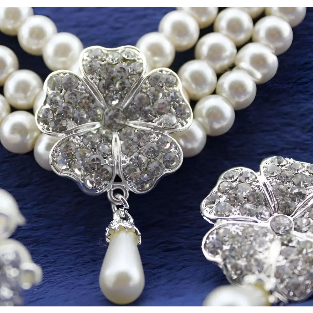 A sparkling silver four-leaf clover brooch with clear crystals and dangling pearl in a three-piece four-leaf clover set