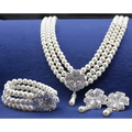 Three-piece silver four-leaf clover necklace and earrings set with pearl strands and matching bracelet for elegant wear