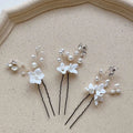 Three sets of white flower u shaped hairpins with pearls and clear crystals featuring delicate wire design