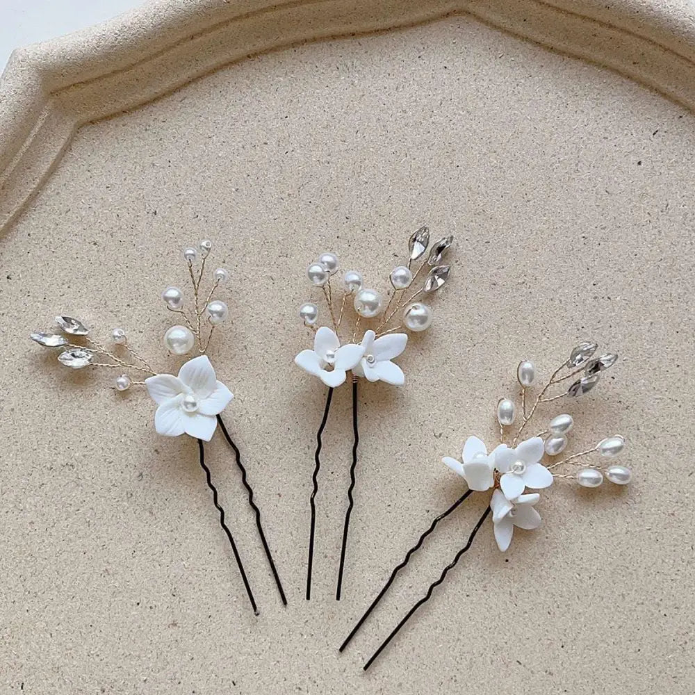 Three sets of white flower u shaped hairpins with pearls and clear crystals featuring delicate wire design