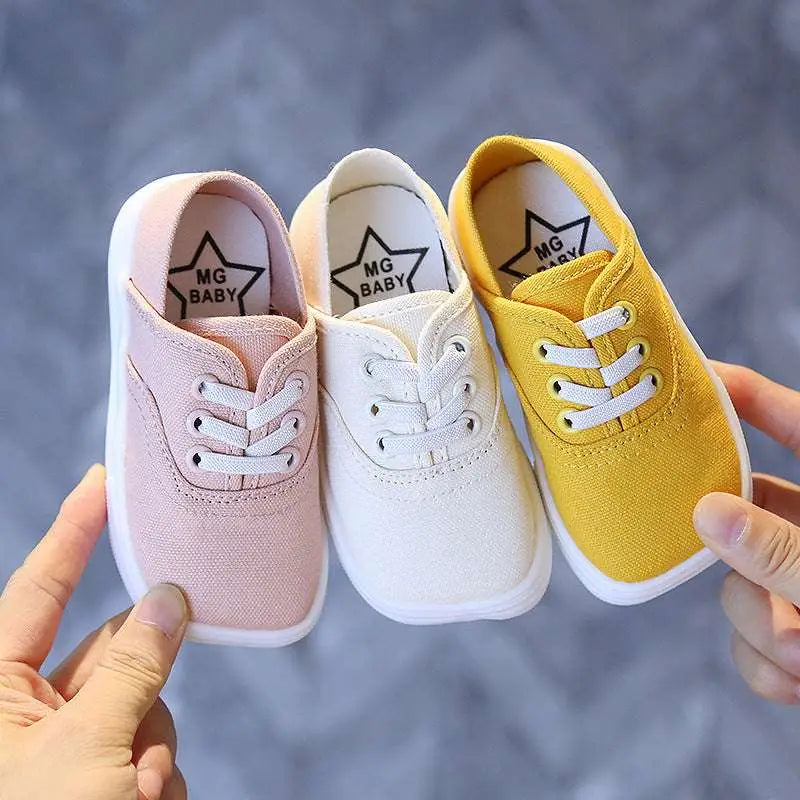 Three toddler canvas shoes korean board shoes in pastel pink, white, and mustard with white rubber soles and mg baby logo