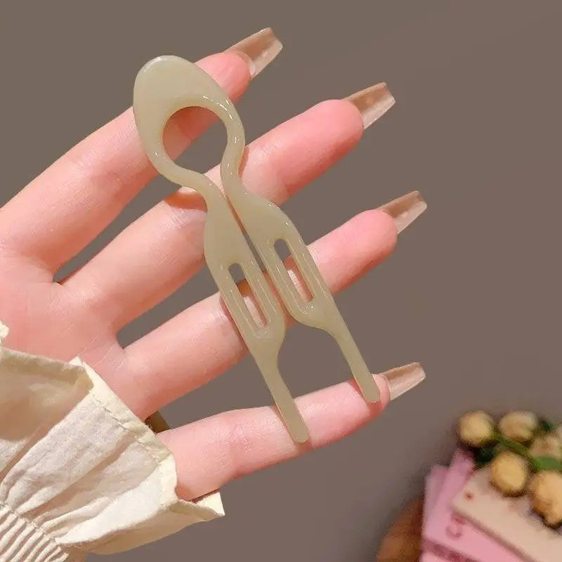 A pair of translucent beige plastic sim card ejector tools with rectangular cutouts for tortoiseshell bun lazy updo gadget use
