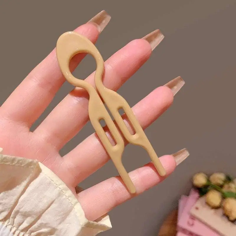 Beige plastic sim card removal tool with looped handle and two prongs for tortoiseshell bun lazy updo gadget styling
