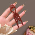 A sleek glossy brown plastic tortoiseshell bun lazy updo gadget hair clip with minimalist looped top and two symmetrical prongs