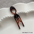 A sleek tortoiseshell bun lazy updo gadget plastic hair comb with two prongs and a smooth glossy finish