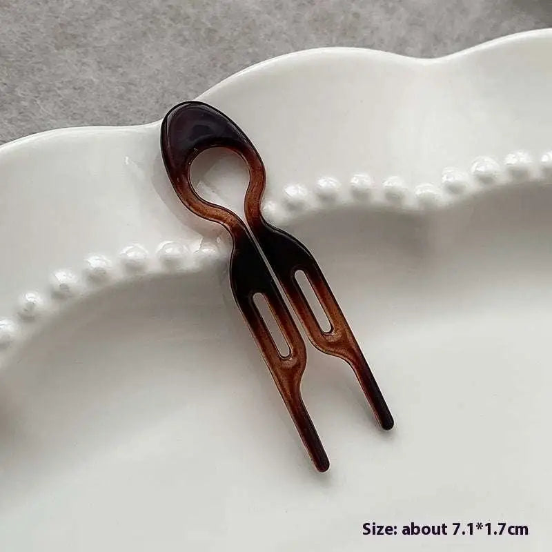 A sleek tortoiseshell bun lazy updo gadget plastic hair comb with two prongs and a smooth glossy finish