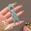 A translucent light blue plastic hair clip shaped like a spoon and fork for tortoiseshell bun lazy updo gadget styling