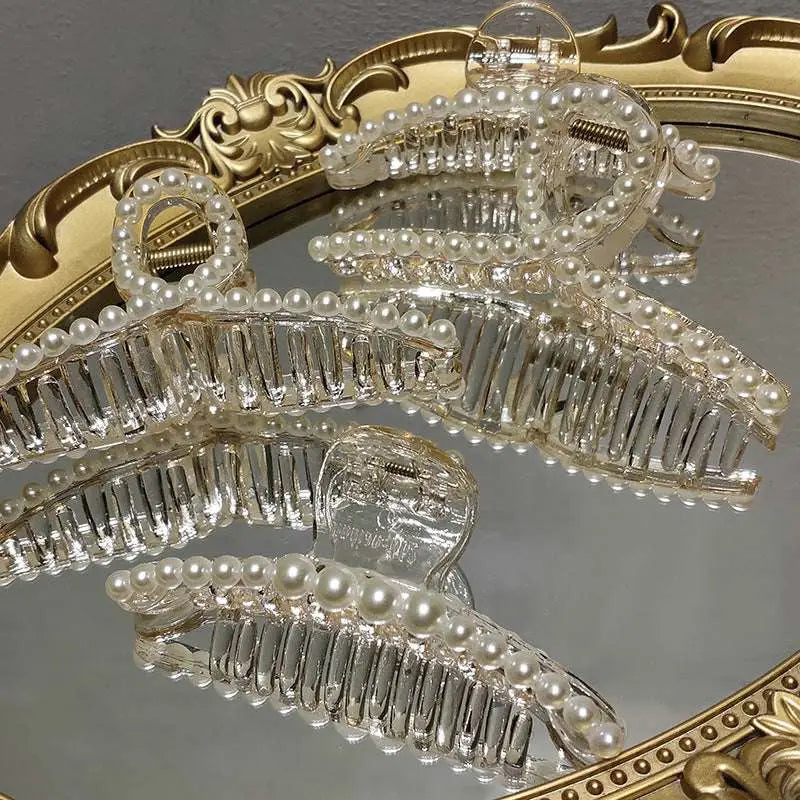 Clear acrylic pearl grab clip with white pearls and a rhinestone bow decoration for elegant hair styling