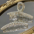 Transparent pearl grab clip made of clear acrylic with a rhinestone bow and white pearl string accents