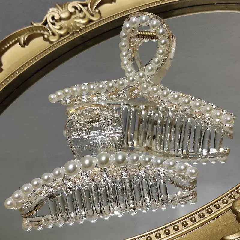 Transparent pearl grab clip made of clear acrylic with a rhinestone bow and white pearl string accents