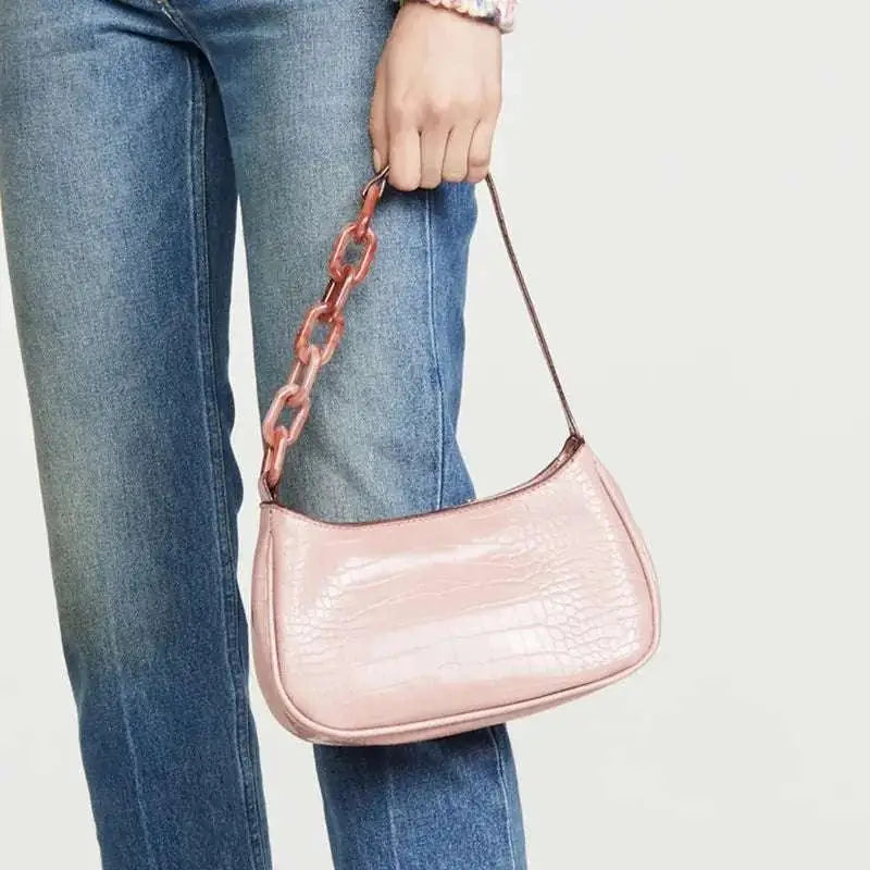 A blush pink trendy small crocodile bag with croc-embossed leather and a translucent rose gold acrylic chain strap