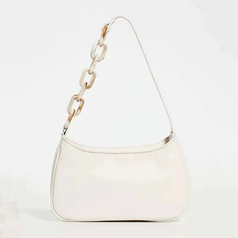 A sleek white leather shoulder trendy small crocodile bag with a distinctive acrylic chain strap featuring bone links