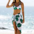 White bikini top and matching wrap skirt in bold green tropical leaf print from tropical leaf bikini printed three-piece set swimsuit