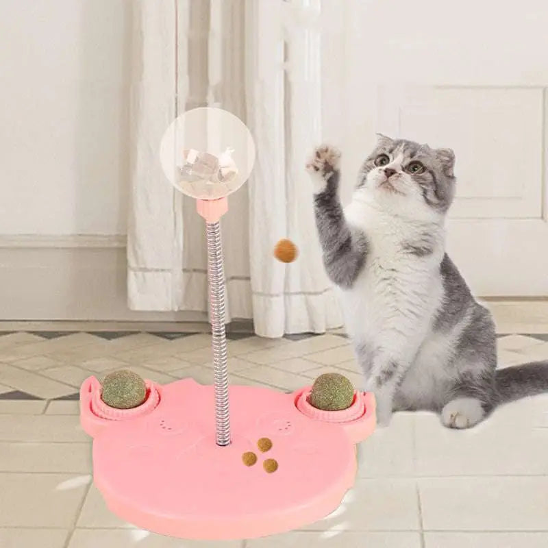 Pink plastic bear-shaped tumbler feeder cat toy with clear ball on flexible pole and green textured side pockets