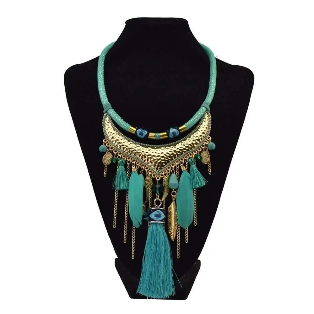 Turquoise gold feather leaf tassel necklace with hammered metal crescent, eye motif, and dangling feather charms