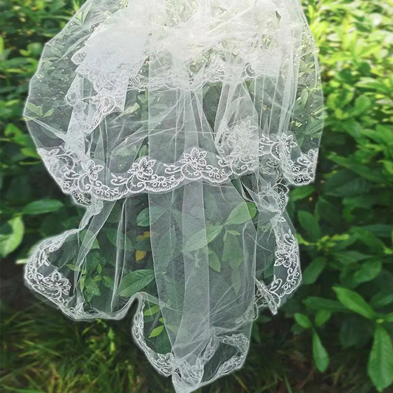A delicate white bridal veil lace headdress with intricate floral embroidery and sheer tulle layers for weddings