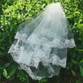 A delicate white bridal veil lace headdress featuring intricate floral embroidery and layered sheer tulle
