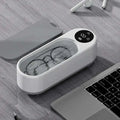 White and gray ultrasonic retainer cleaner machine with digital display showing temperature for dental care