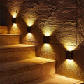 Black rectangular wall-mounted solar powered garden lights with warm yellow illumination using solar power technology