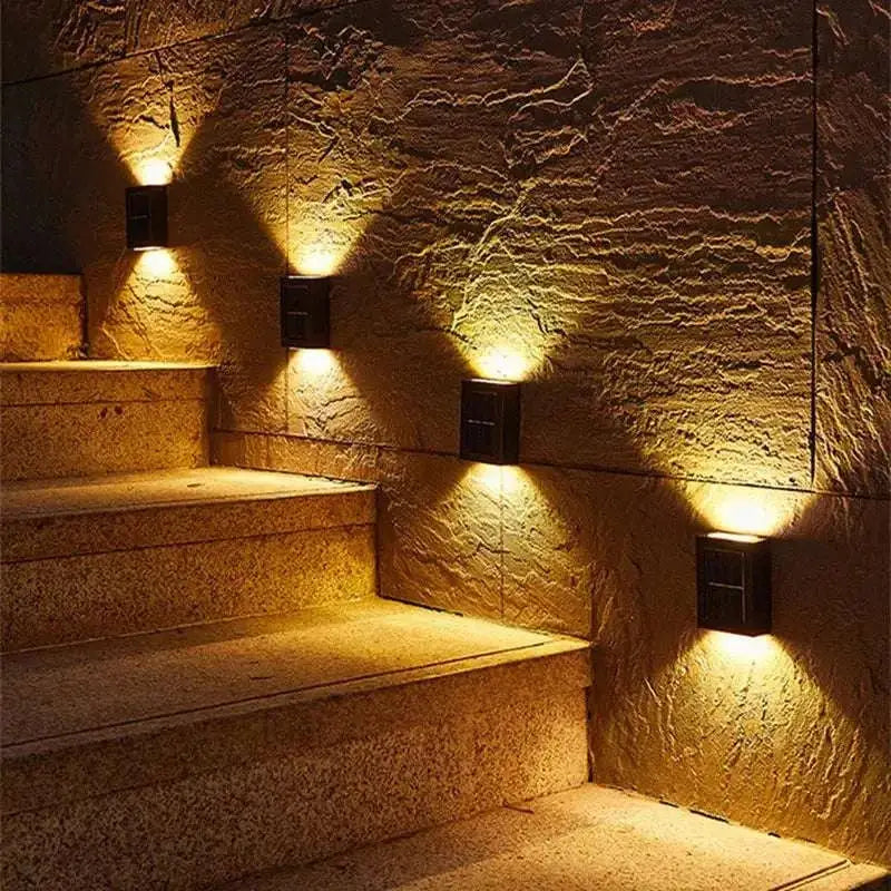 Black rectangular wall-mounted solar powered garden lights with warm yellow illumination using solar power technology