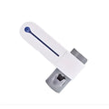 White plastic child safety lock with blue button and gray metallic parts on the back of a sterilizing toothbrush holder and toothpaste dispenser