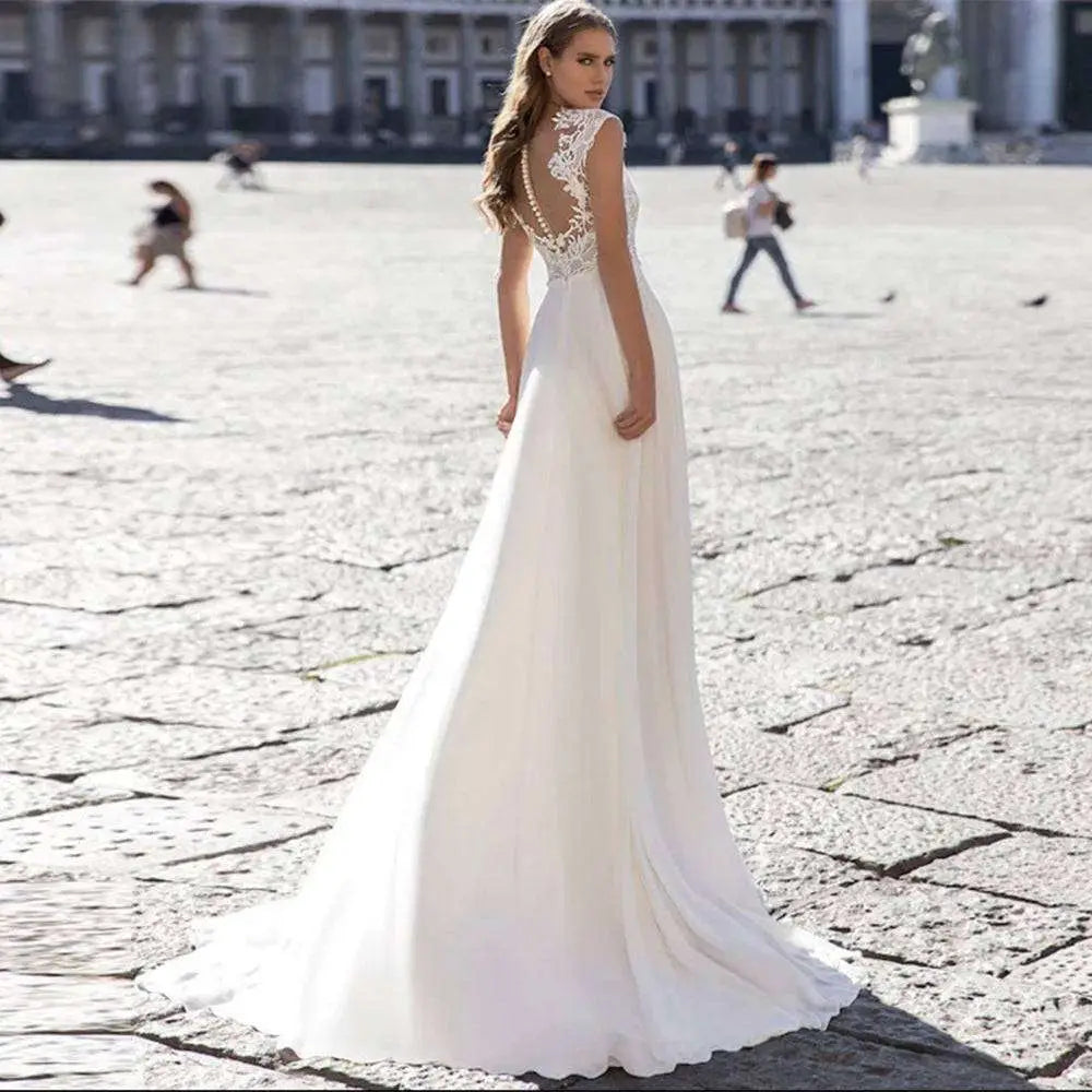 Back view of a flowing white chiffon wedding dress with lace sleeves and intricate lace detailing on the v-neck lace back