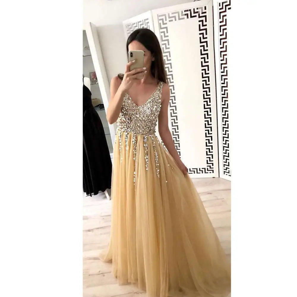A shimmering gold v-neck sequined floor-length dress with a beaded bodice and flowing tulle skirt