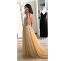 Back view of a shimmering gold v-neck sequined floor-length dress with intricate beaded embellishments and flowing tulle skirt