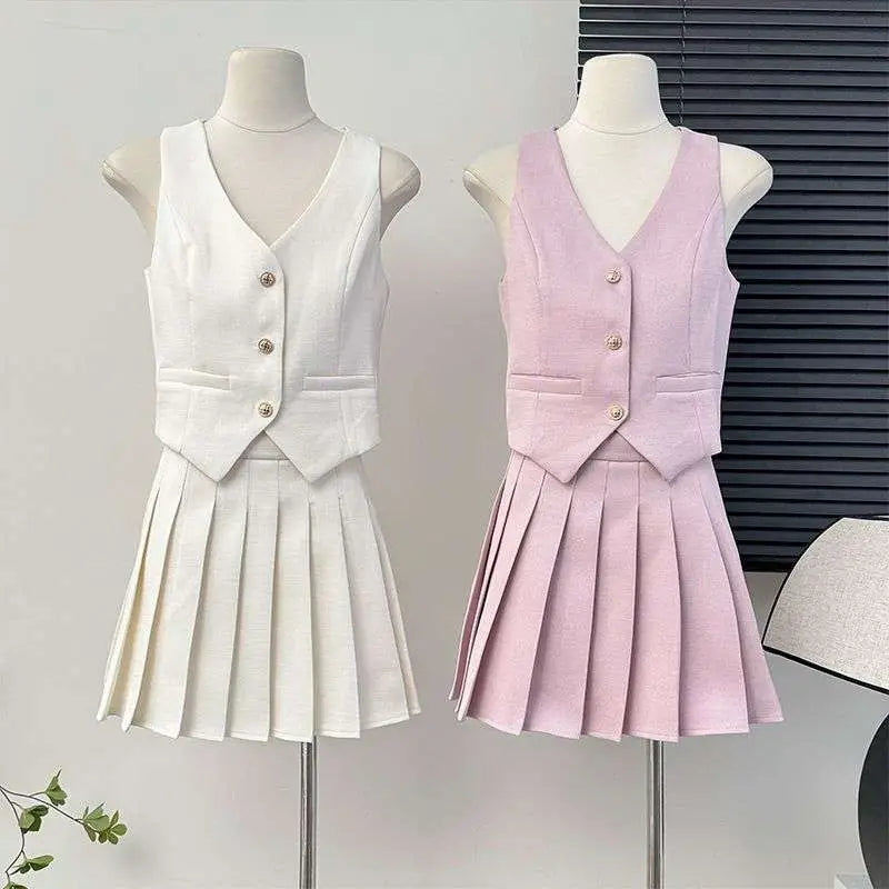 A white and pale pink high waist pleated skirt two-piece set with a v-neck vest and gold-toned apricot waistcoat buttons