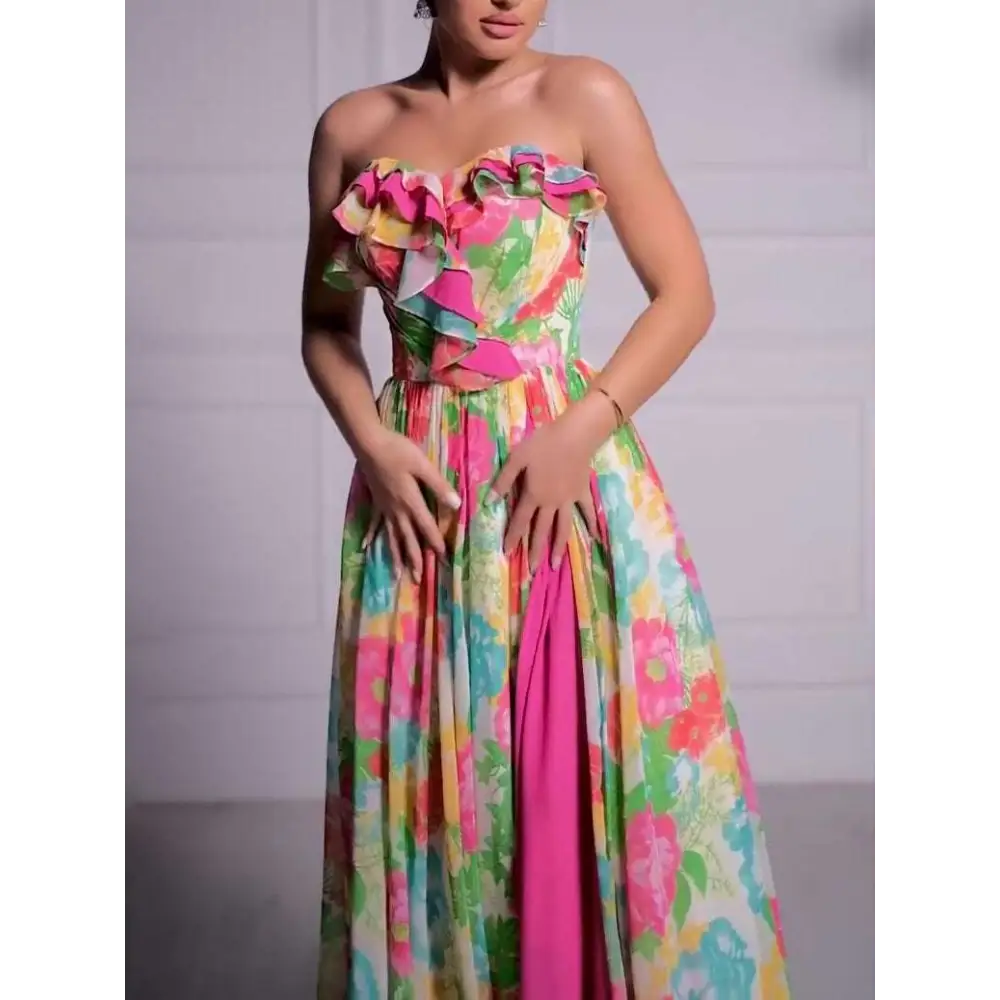 A vibrant strapless floral print maxi dress with ruffled bodice detailing and a bold pink side slit