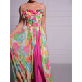 A vibrant strapless floral print maxi dress with a ruffled bodice and bold pink side slit for elegant occasions