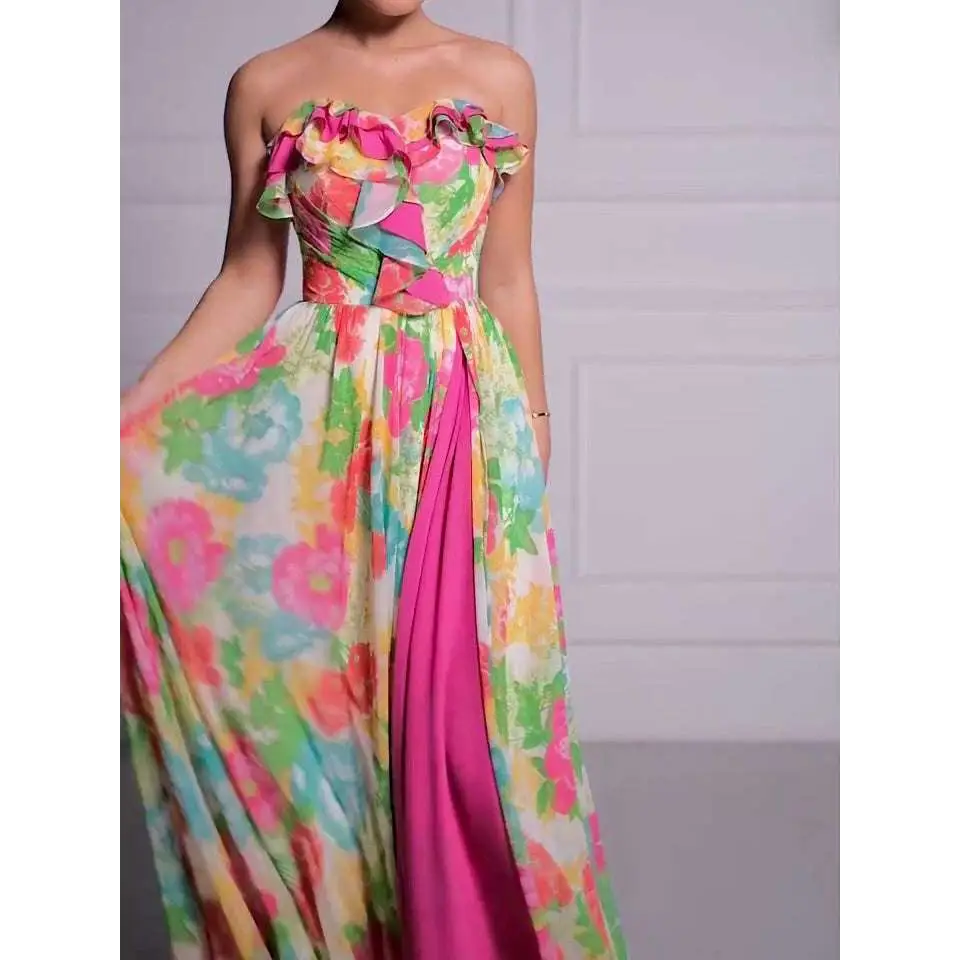 A vibrant strapless floral print maxi dress with a ruffled bodice and bold pink side slit for elegant occasions